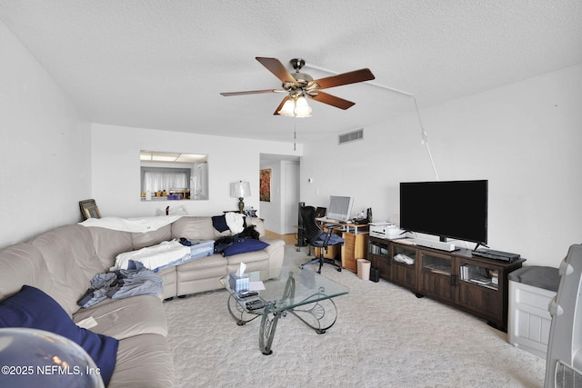 living room featuring ceiling fan, light carpet, and a textured ceiling