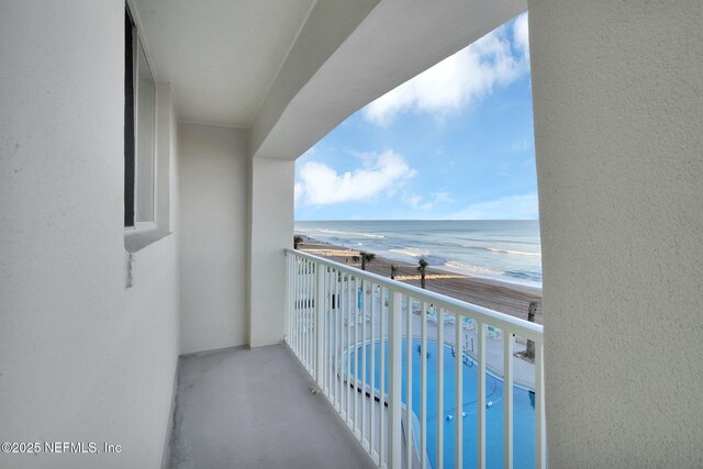 balcony featuring a beach view and a water view