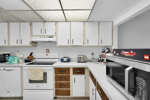 kitchen featuring white appliances, a paneled ceiling, and white cabinets