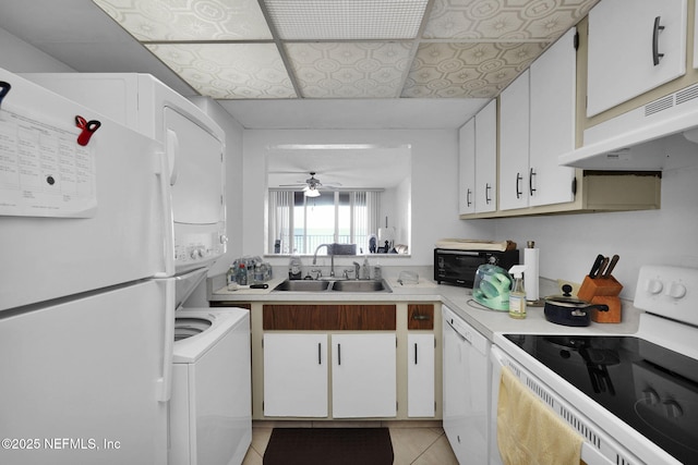 kitchen featuring stacked washer / drying machine, sink, white cabinetry, light tile patterned floors, and white appliances