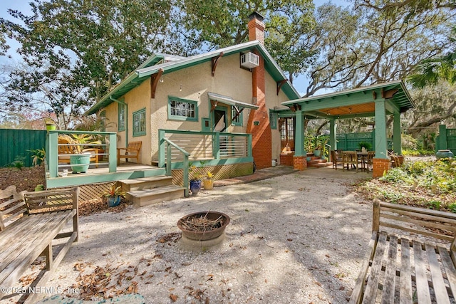 back of house with a patio area, a deck, a wall mounted AC, and an outdoor fire pit