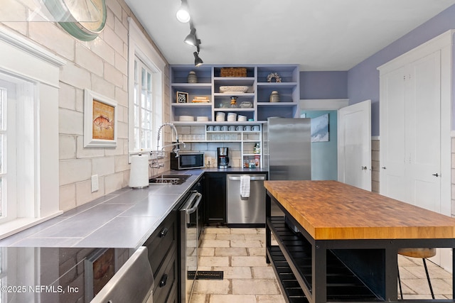 kitchen featuring sink, a breakfast bar area, stainless steel counters, stainless steel dishwasher, and backsplash