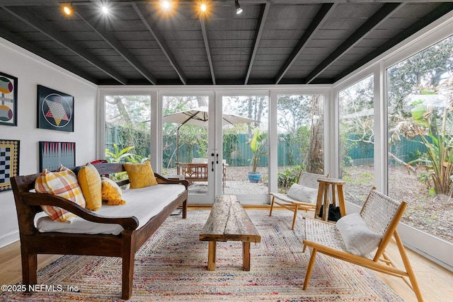 sunroom featuring beamed ceiling and a healthy amount of sunlight