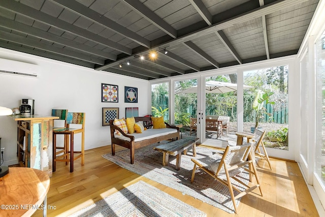 sunroom with beamed ceiling, a wall mounted air conditioner, rail lighting, and plenty of natural light