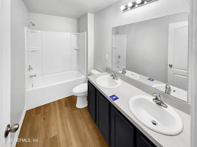 full bathroom featuring toilet, wood-type flooring, tub / shower combination, a textured ceiling, and vanity