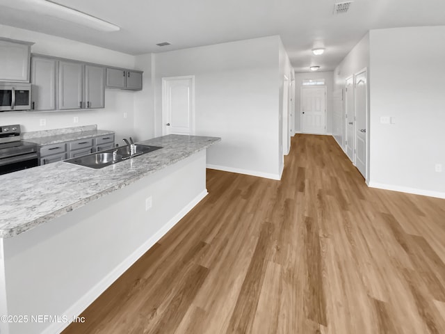 kitchen with gray cabinetry, sink, wood-type flooring, and stainless steel appliances