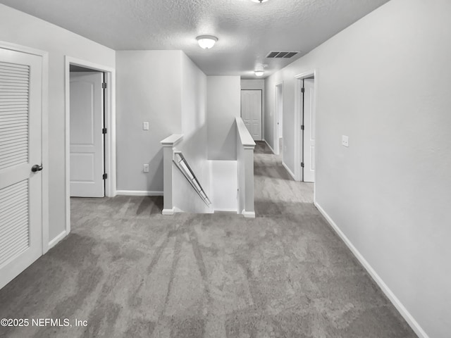 hallway featuring light colored carpet and a textured ceiling