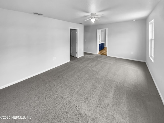 spare room featuring dark colored carpet and ceiling fan