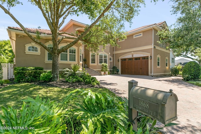 mediterranean / spanish-style house featuring a garage and a front lawn