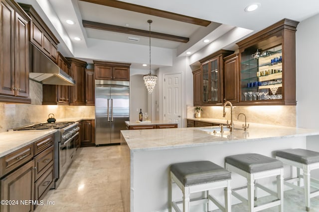 kitchen with high quality appliances, a kitchen bar, kitchen peninsula, and sink