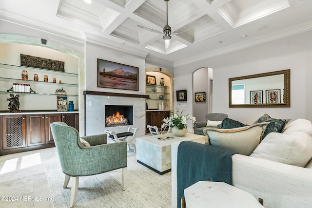 living room with coffered ceiling, ornamental molding, a fireplace, and built in features