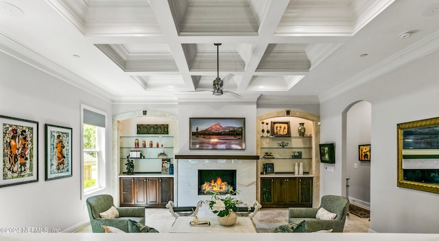 living room with built in features, a premium fireplace, ceiling fan, beam ceiling, and coffered ceiling