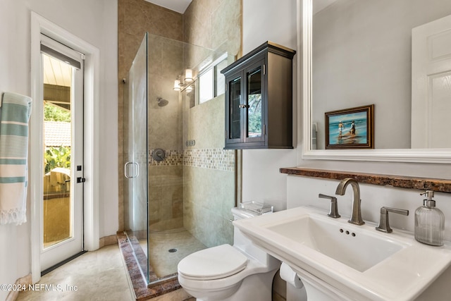 bathroom with a shower with door, sink, and toilet