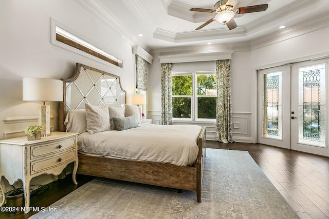 bedroom featuring dark hardwood / wood-style floors, ornamental molding, access to outside, a tray ceiling, and french doors