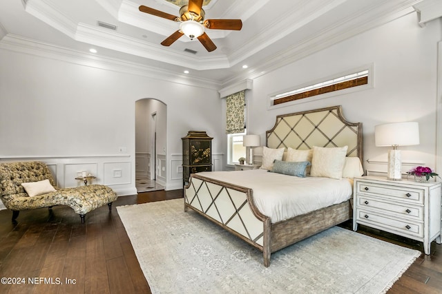 bedroom featuring dark wood-type flooring, ceiling fan, a tray ceiling, and crown molding