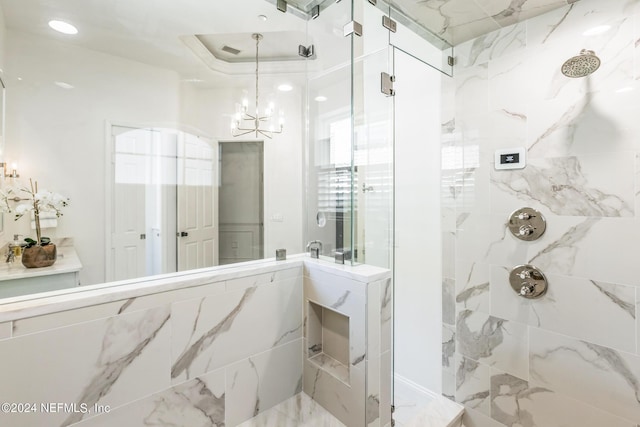 bathroom featuring an inviting chandelier, tiled shower, and a tray ceiling