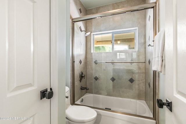 bathroom featuring enclosed tub / shower combo and toilet