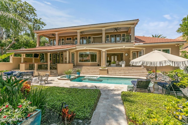 back of property with a pool with hot tub, a balcony, a patio, and ceiling fan