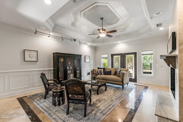 living room featuring ornamental molding, plenty of natural light, a tray ceiling, and a premium fireplace