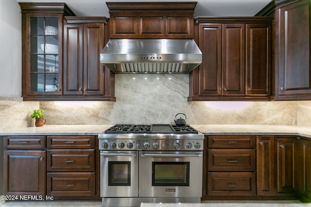 kitchen with range with two ovens, dark brown cabinetry, and range hood