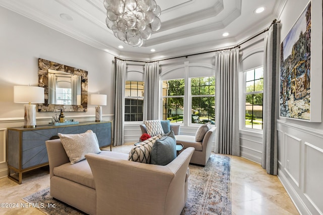 living room featuring an inviting chandelier, ornamental molding, and a tray ceiling