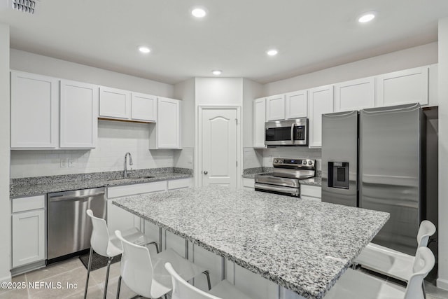 kitchen featuring stainless steel appliances, sink, a breakfast bar area, and white cabinets