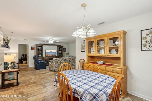 dining area featuring ceiling fan with notable chandelier and light hardwood / wood-style flooring