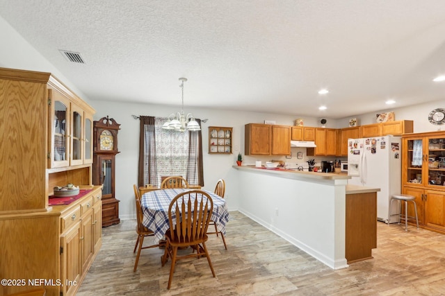 kitchen with pendant lighting, light hardwood / wood-style flooring, white refrigerator with ice dispenser, kitchen peninsula, and a chandelier