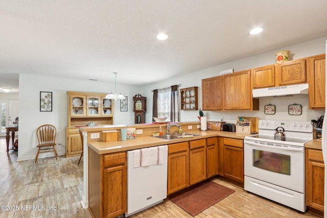 kitchen with sink, white appliances, light hardwood / wood-style flooring, hanging light fixtures, and kitchen peninsula