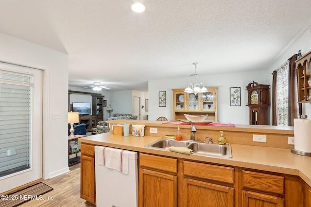 kitchen featuring sink, hanging light fixtures, a textured ceiling, dishwasher, and ceiling fan with notable chandelier