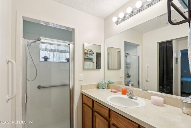 bathroom featuring an enclosed shower, vanity, and a textured ceiling