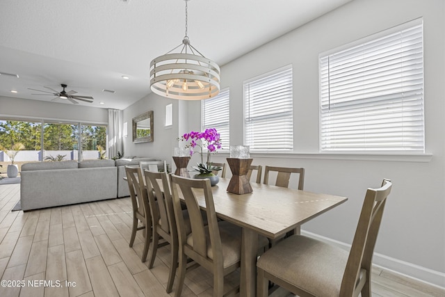 dining area with ceiling fan with notable chandelier and light hardwood / wood-style floors