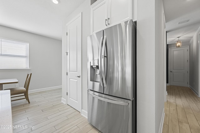 kitchen featuring stainless steel fridge with ice dispenser, light hardwood / wood-style flooring, and white cabinets