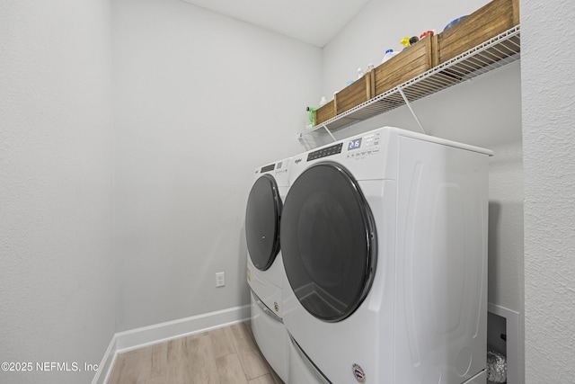 clothes washing area featuring washer and dryer and light hardwood / wood-style flooring