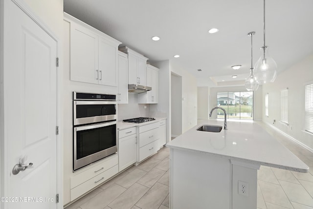 kitchen with a center island with sink, a sink, gas stovetop, stainless steel double oven, and white cabinets