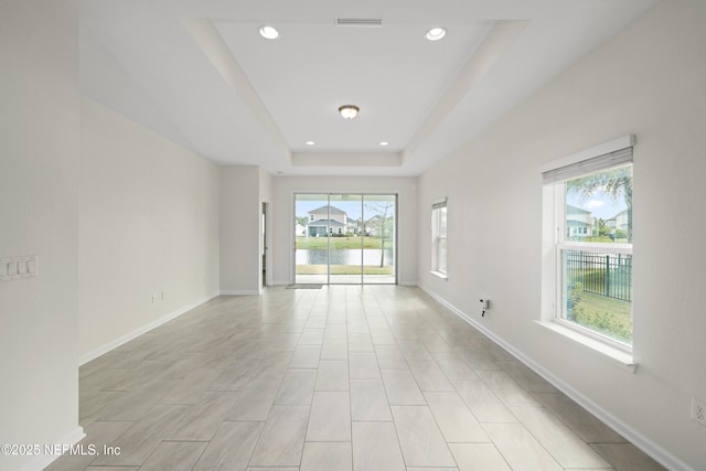 empty room with recessed lighting, baseboards, a raised ceiling, and visible vents