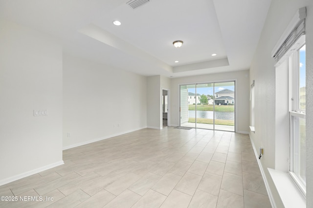 empty room featuring visible vents, recessed lighting, a raised ceiling, and baseboards