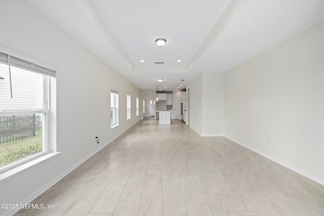 hallway featuring a tray ceiling, recessed lighting, and baseboards