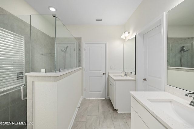 full bathroom with a stall shower, two vanities, and a sink