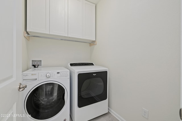 washroom with light tile patterned floors, cabinet space, washer and dryer, and baseboards