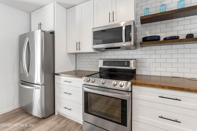 kitchen with butcher block countertops, tasteful backsplash, white cabinetry, light hardwood / wood-style floors, and stainless steel appliances