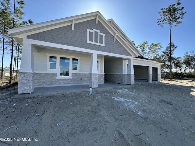 craftsman-style home with a garage, stone siding, and driveway