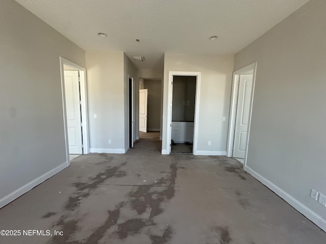 unfurnished bedroom featuring concrete floors, a textured ceiling, and baseboards