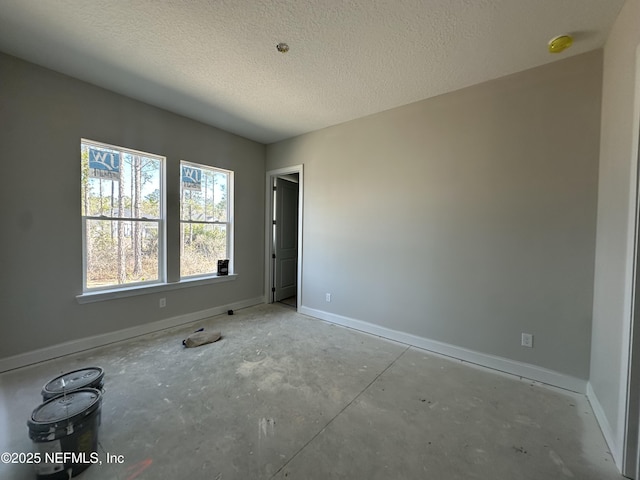 spare room featuring baseboards and a textured ceiling