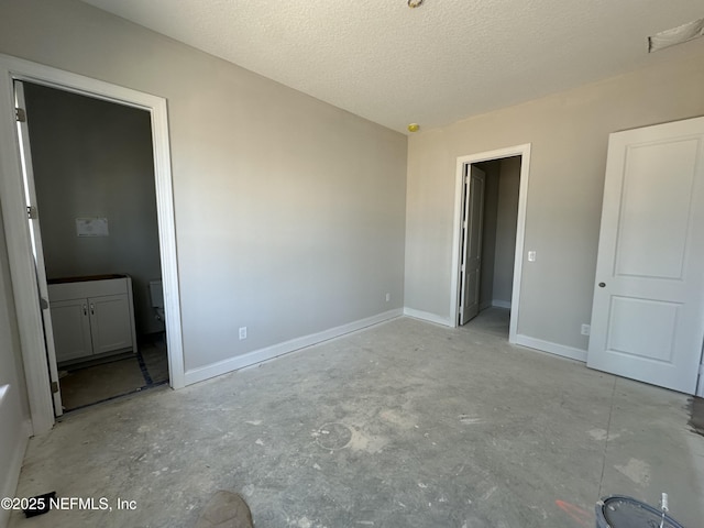 unfurnished bedroom featuring baseboards, unfinished concrete flooring, and a textured ceiling