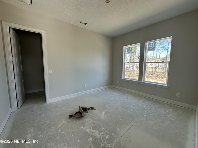 empty room with baseboards and a textured ceiling