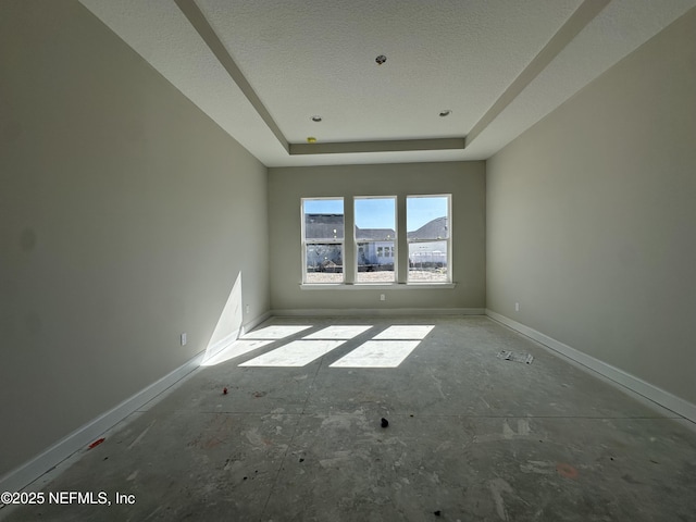 unfurnished room with a tray ceiling and baseboards