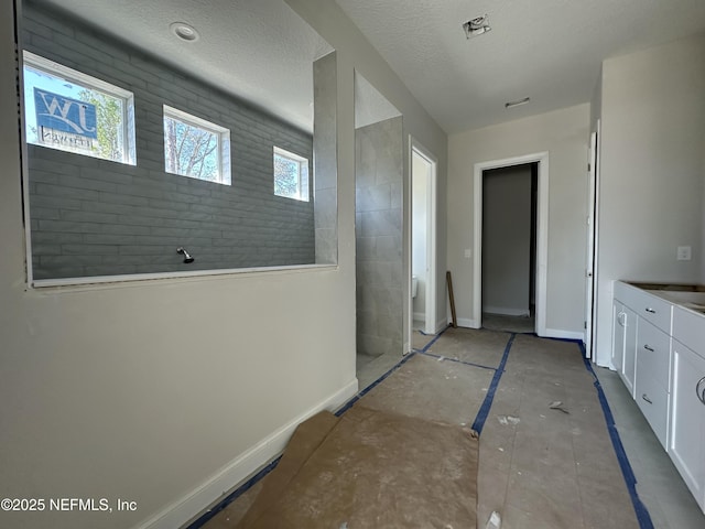 interior space with a textured ceiling and baseboards