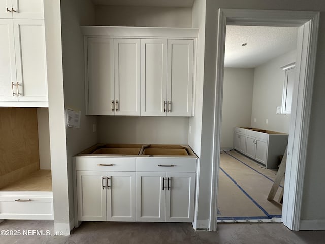 kitchen featuring a textured ceiling and white cabinets