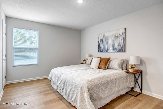 bedroom with light hardwood / wood-style floors and a textured ceiling